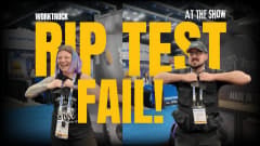 Two people at a trade show attempt to tear durable Tiger Tough seat cover fabric during a rip test challenge, but fail to rip it.