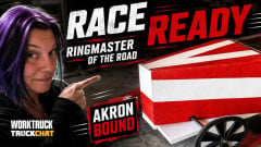 Lauren Fletcher points toward the red-and-white Ringmaster of the Road soap box derby car. Bold text reads “Race Ready,” “Ringmaster of the Road,” and “Akron Bound.”