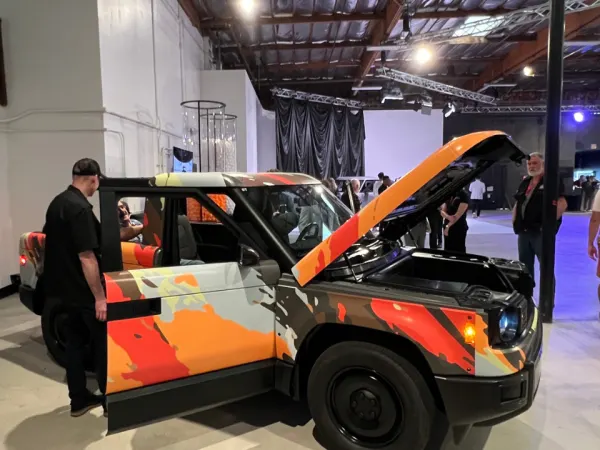 Attendees looking at a Slate pickup truck wrapped in colorful flair.