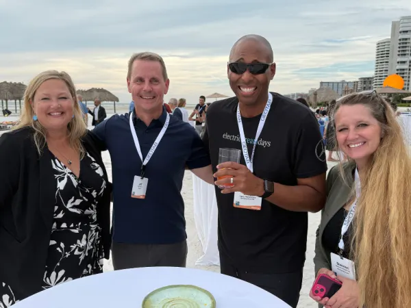 A group gathers for a photo at a beach networking event.