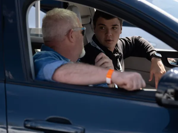 Two men in parked car conversing. 