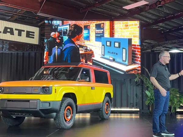 CEO Peter Faricy on stage in front of a yellow Slate vehicle.