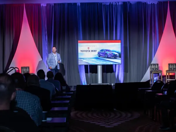 Man on stage conducting business meeting. 