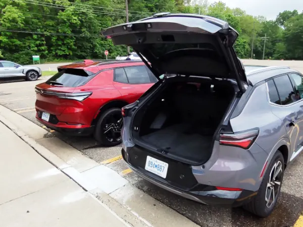 Two small SUVs parked, viewed from rear-quarter angle, rear hatch is open on one on right.