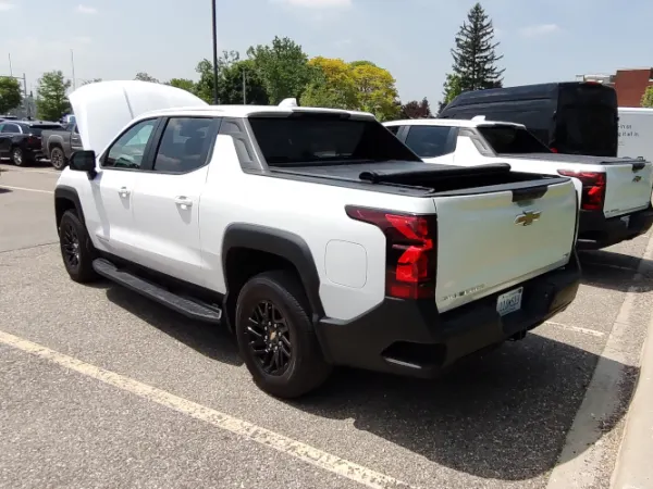 Rear quarter view of the left side of a white EV pickup truck.