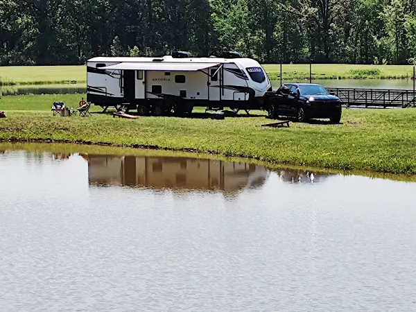 Black pickup truck hitched to a camper parked beside a lake.