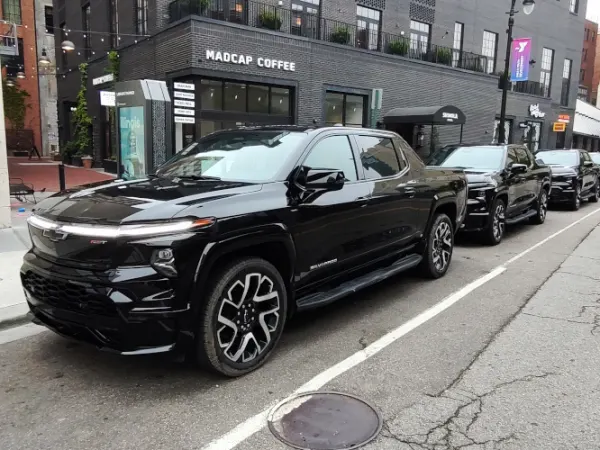 A row of black pickup trucks shown parked in downtown Detroit.