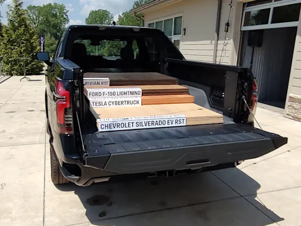 Varying lengths of word panels stacked in the back of a black pickup truck.