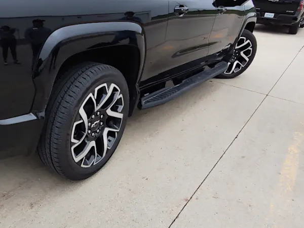 Close-up view of a black pickup truck with front wheels turned to the right and rear wheels turned in the opposite direction to demonstrate all-wheel-steering.