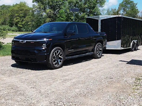 Black pickup truck towing a black enclosed cargo trailer.