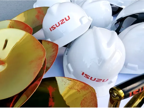 A collection of Isuzu hardhats and shovels, which have a dusting of red dirt.