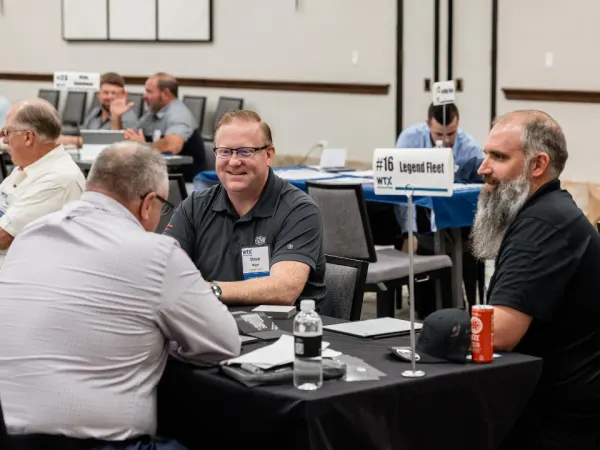 Three attendees in active discussion at a Work Truck Exchange one-on-one meeting.
