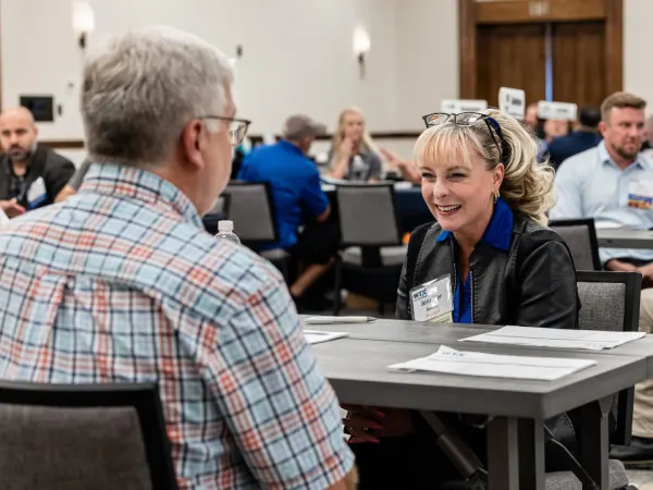Two attendees smiling as they talk during a Work Truck Exchange one-on-one session.
