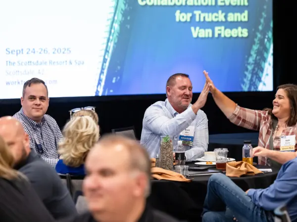 Fleet managers and suppliers high-fiving and laughing during an outdoor networking activity at Work Truck Exchange 2025.