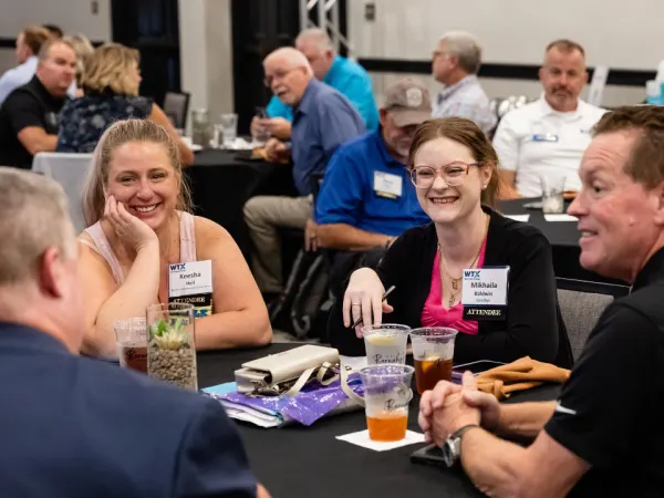 Attendees smiling and chatting at a round table during a networking session at Work Truck Exchange 2025.