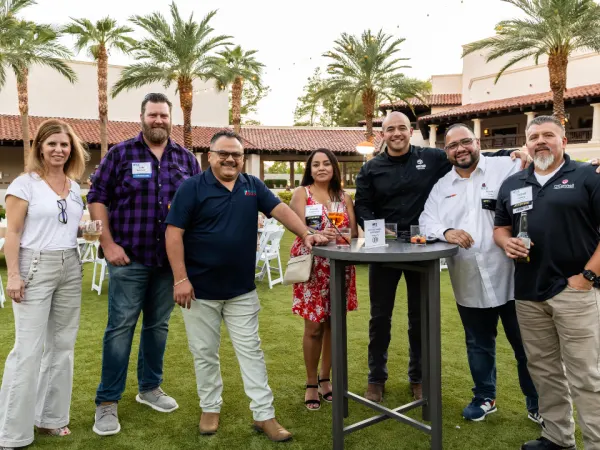 Group of Work Truck Exchange 2025 attendees posing together and enjoying drinks during the outdoor evening reception.
