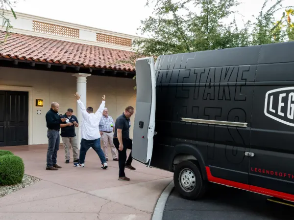 Attendees outside the Legend Fleet axe-throwing van during Work Truck Exchange 2025, with one participant celebrating a successful throw.