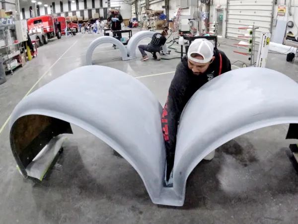 Technician reaching between two sections of a fender for two wheels.