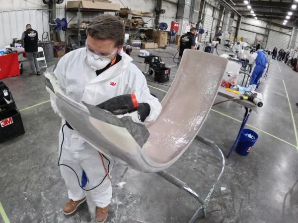 Technician repairing a fender in a body shop.