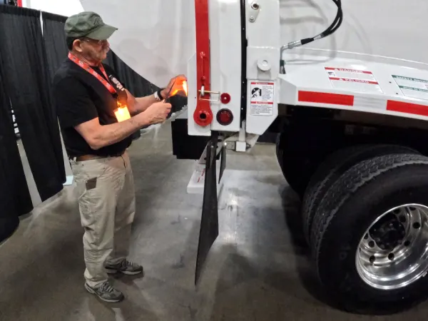 Man working on tail light of a garbage truck.
