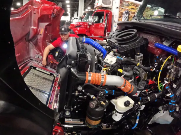 Man reaching inside of a large diesel engine to make a repair.
