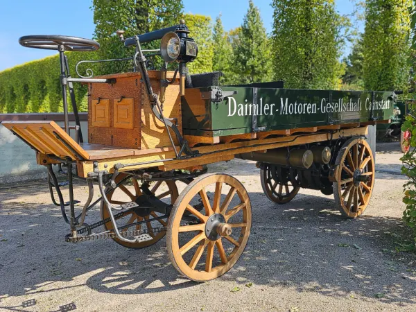 Reconstructed 1896 Daimler motorized truck with wooden wheels and rear-mounted engine, considered the world’s first truck.