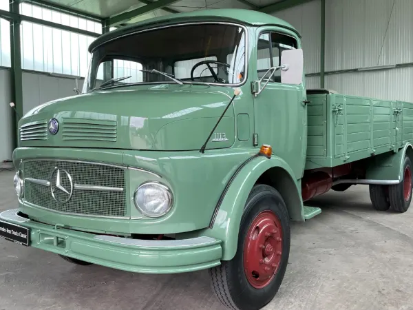 Light green restored Mercedes-Benz classic truck inside a showroom, representing mid-20th century commercial vehicle design.