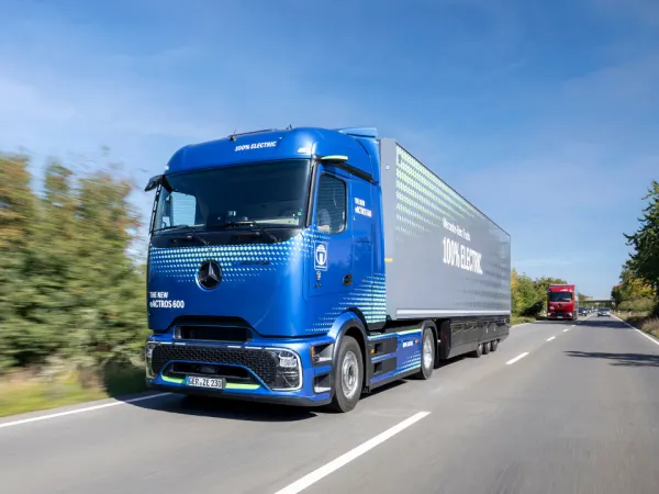 Blue Mercedes-Benz eActros 600 electric semi-truck driving on a highway, highlighting modern battery-electric heavy-duty transport.