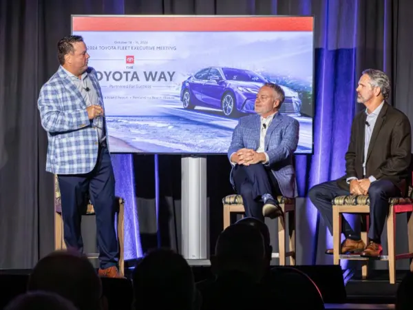 Man discussing corporate business with two associates on stage. 