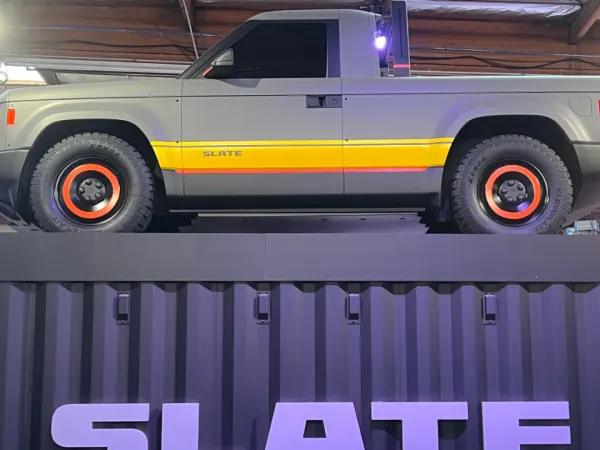 A gray pickup truck atop a rectangular platform bearing the Slate logo.