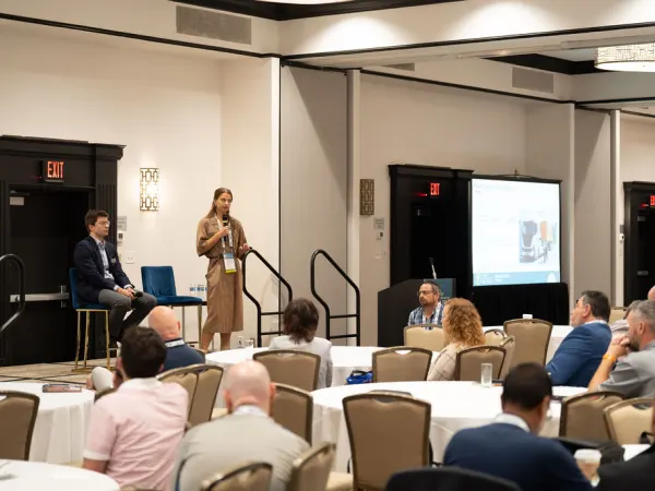 Woman on stage making presentation in front of attendees. 