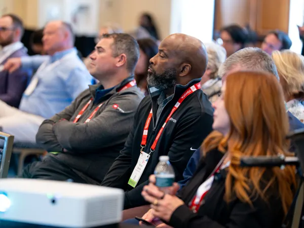 Two people listen to a conference session at FFC2026