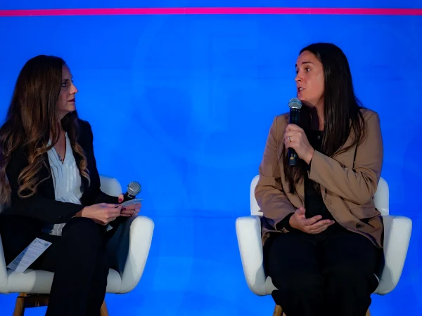 Diana Holland and Erin Farrell face each other while Erin holds a microphone