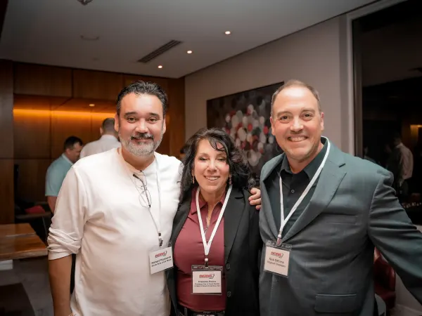three pose for photo at cocktail party.