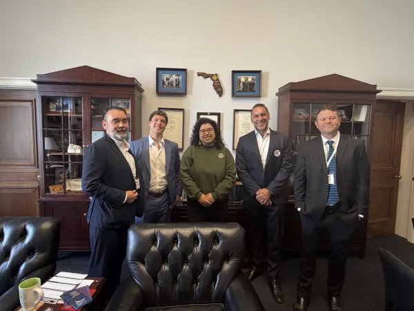 five pose for a photo in a congressperson's office