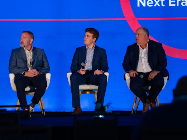 Three men sit on a stage at FFC talking about EVs at scale.
