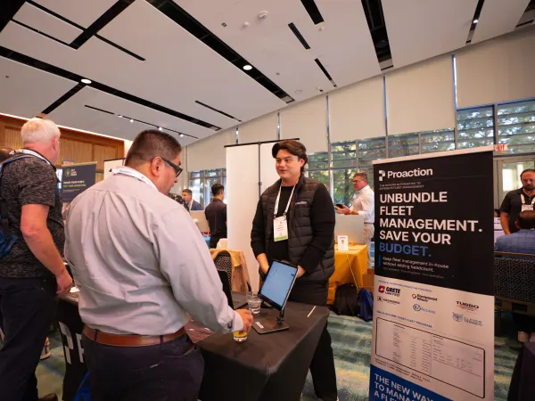 A Proaction representative speaks with two attendees at the company's exhibitor booth during the 2026 Fleet Forward Conference.