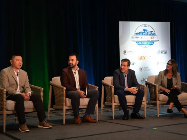 Four people sitting on stage doing presentation. 