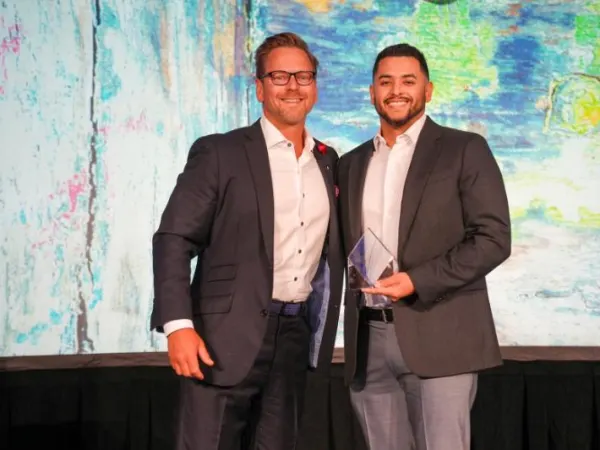Award winner poses with another man on stage.