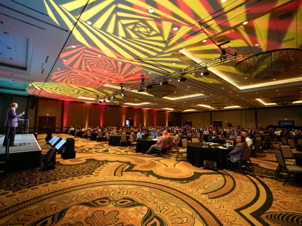 Wide shot of main ballroom with attendees sitting.