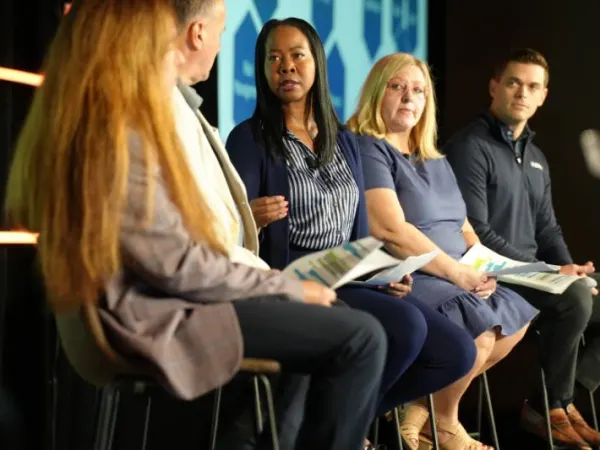 Five panelists on stage for a seminar.