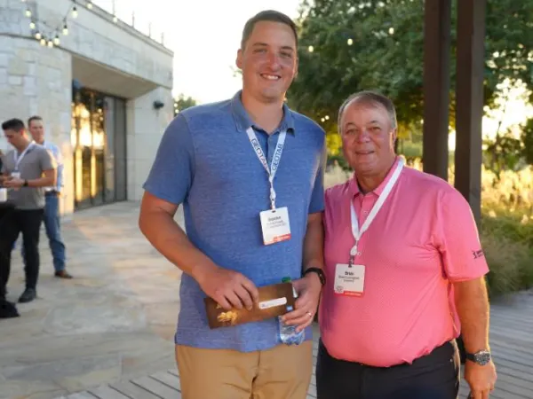 Winning golfer poses with host outside.