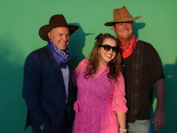 Three attendees dress as cowboys with green screen in background.