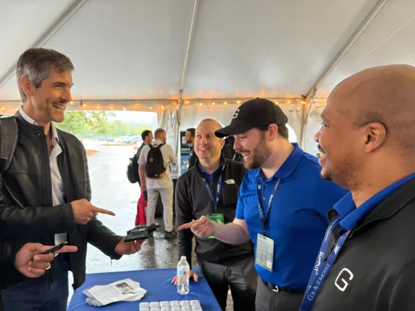 Attendees converse in at vendor's table in exhibit hall.