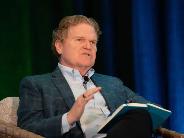 Man in chair talks during presentation. 