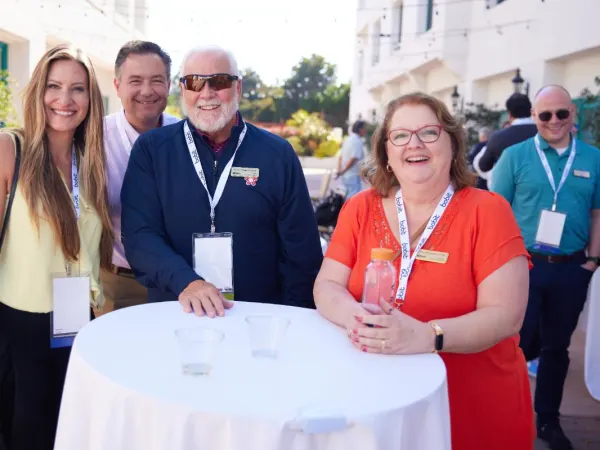 Three event attendees pose at a cocktail table. 