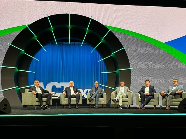 Six executives sit on stage during a seminar. 