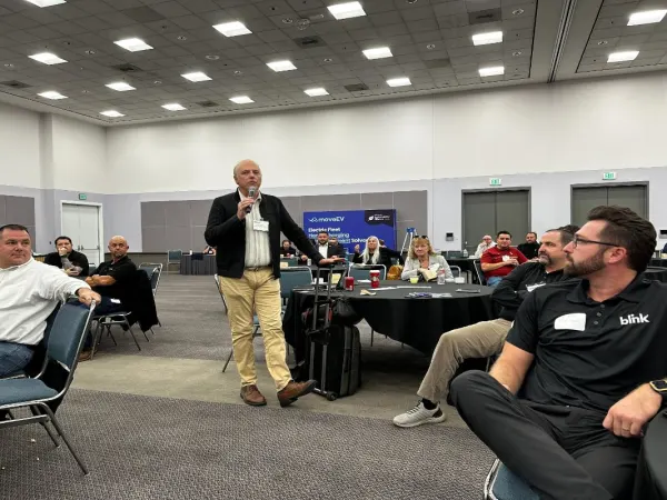 Photo of man with microphone in audience asking a question during a seminar at LA Auto Show.
