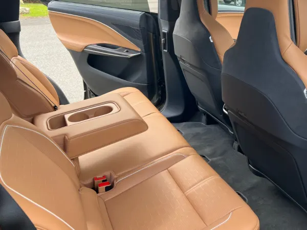 Ride side view of two rear passenger seats separated by armrest with two cupholders.