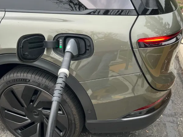 Rear back portion of the EV with charging cable docked in port.